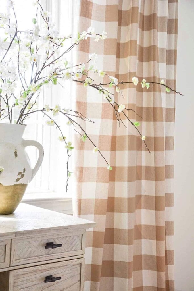 Realistic faux flowering branches arranged in a white urn on a bedside table