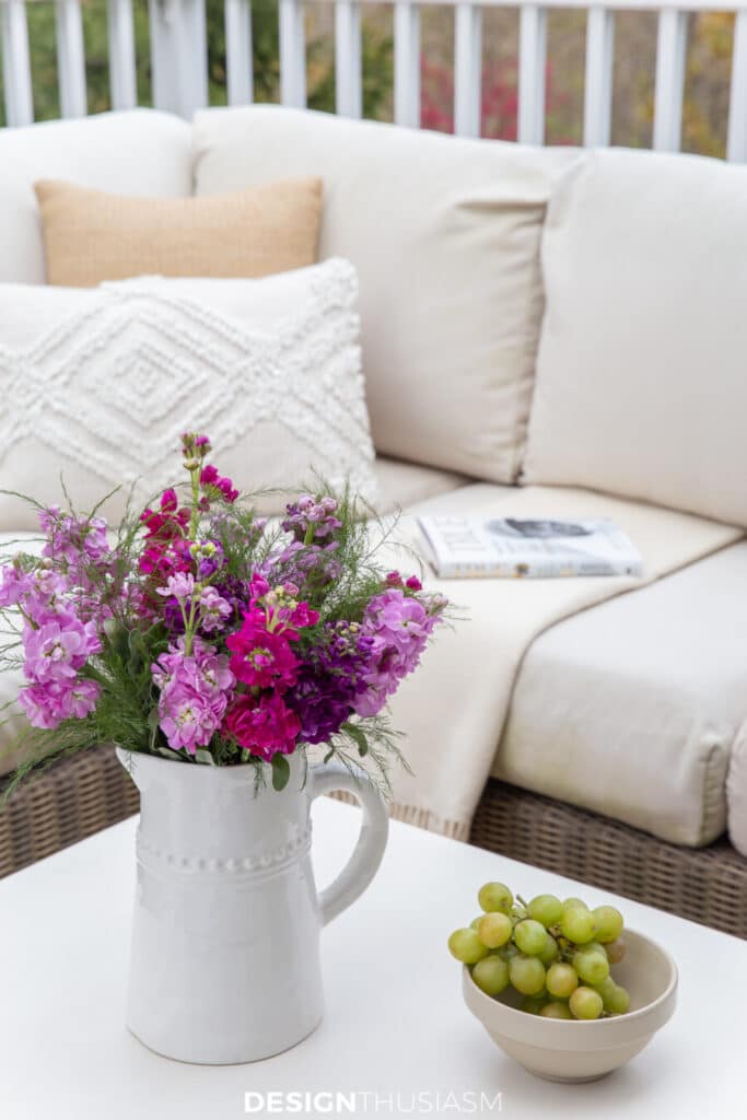 sectional on deck with a vase of flowers on the coffee table