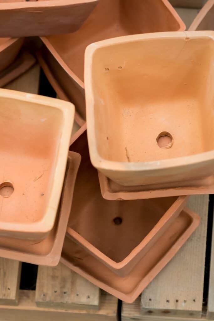 overhead view of multiple terracotta pots in various sizes stacked together showing drainage holes in the bottom of each pot