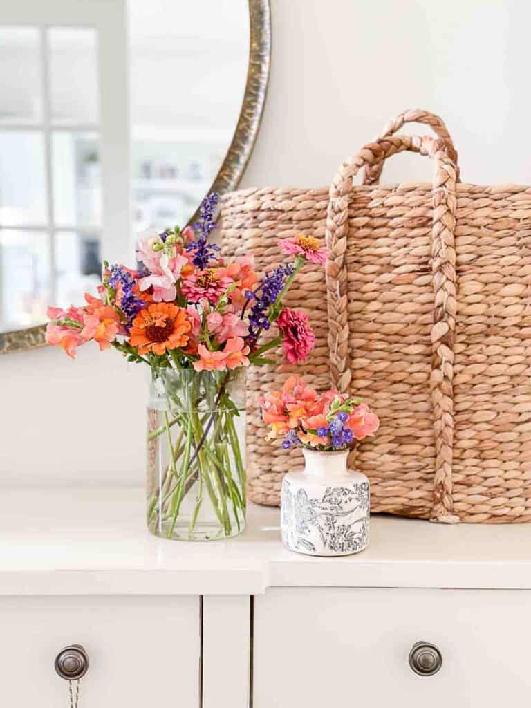 foyer table with a wicker basket and cut flowers in vases