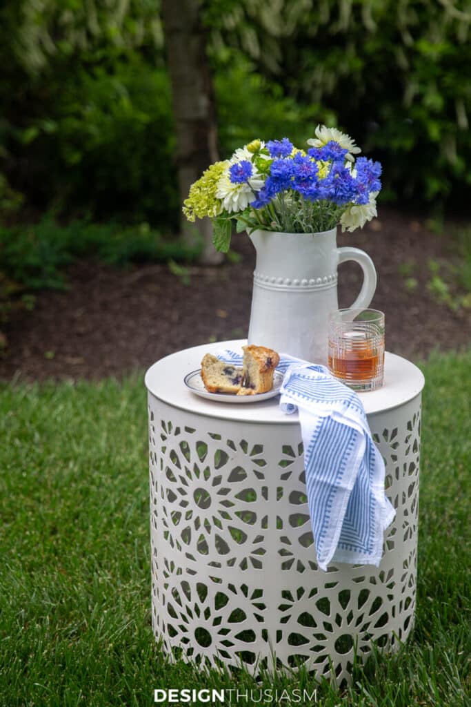 outdoor garden stool with flower, a muffin and a drink on it.