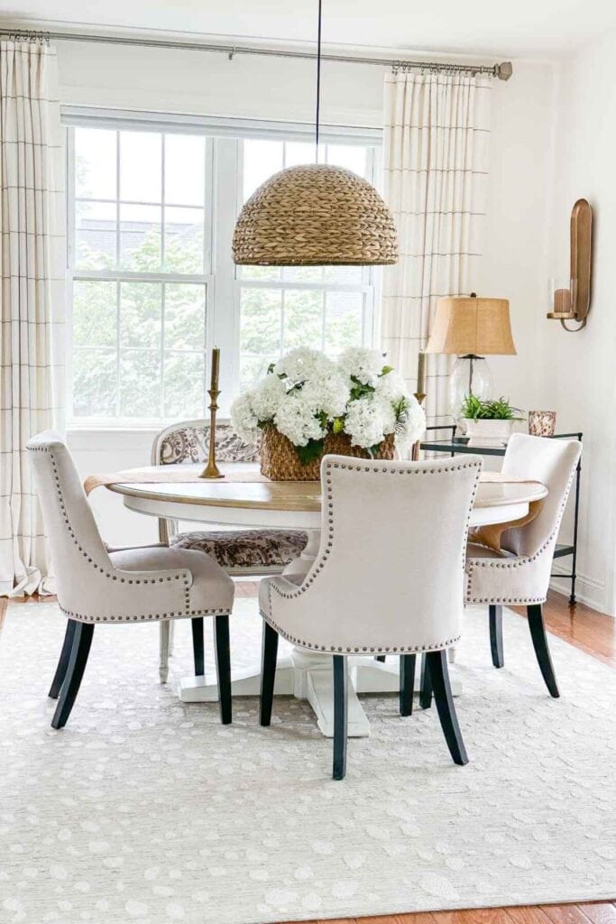 simple dining table centerpiece ideas with white flowers in a basket and candles on a round table
