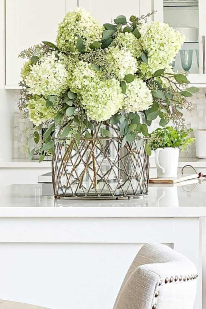 green hydrangeas in a large glass vase on a kitchen counter