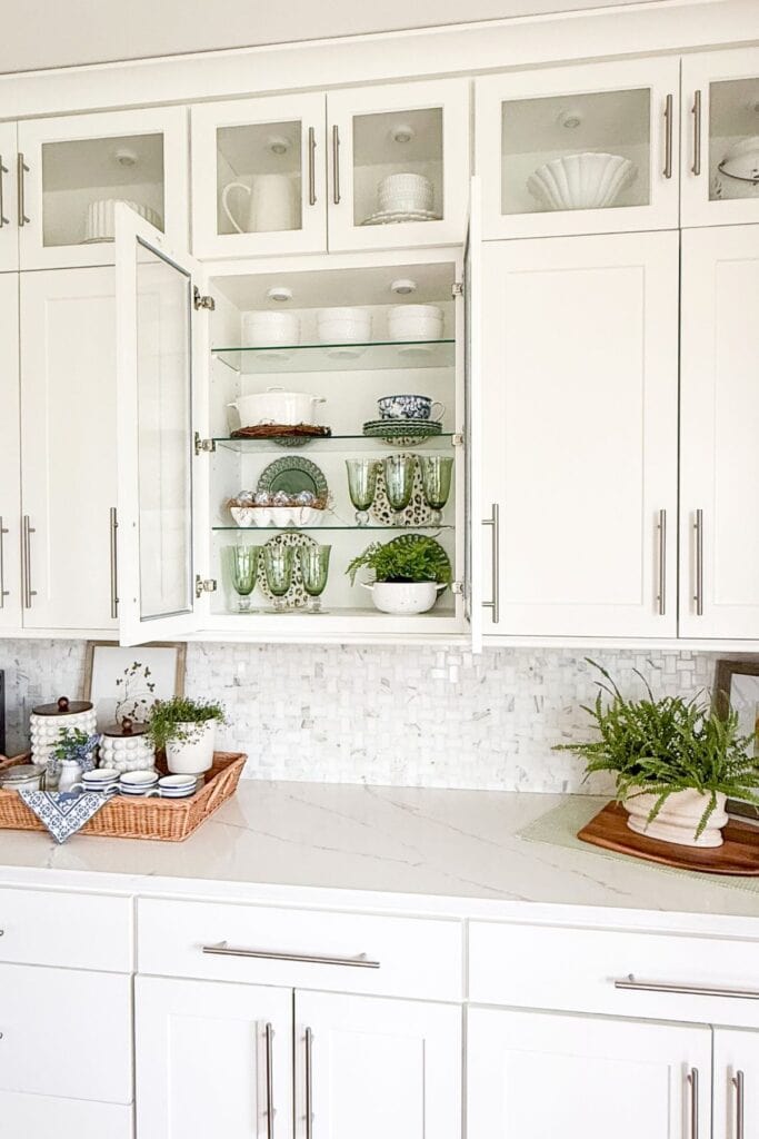 simple kitchen ideas styling glass cabinets with dishes, green glassware, and plants in a white kitchen