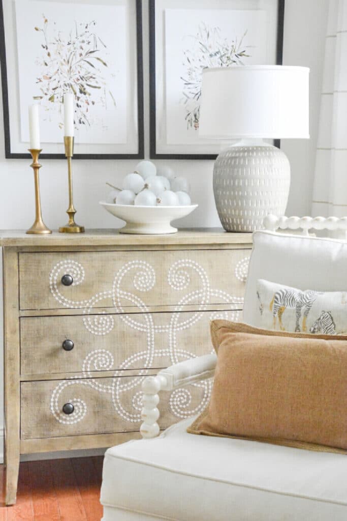 a chest with candles, a bowl of large frosted beads and a lamp on it.
