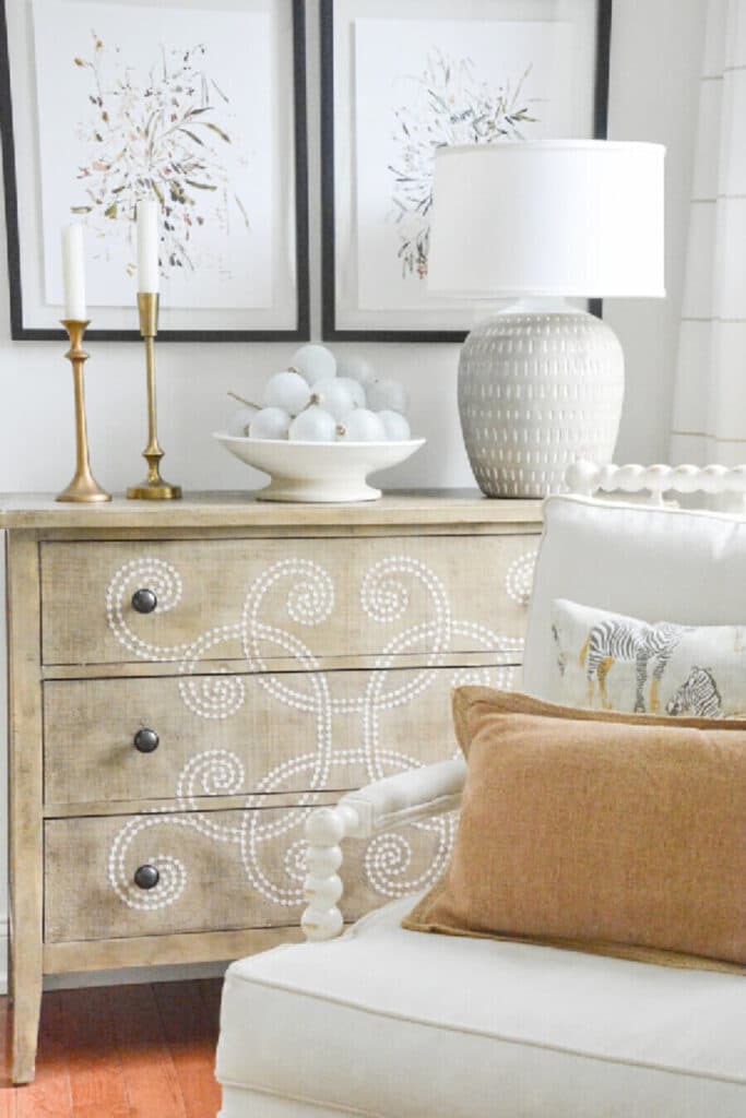 chest with pictures above it and a chair in the foreground.