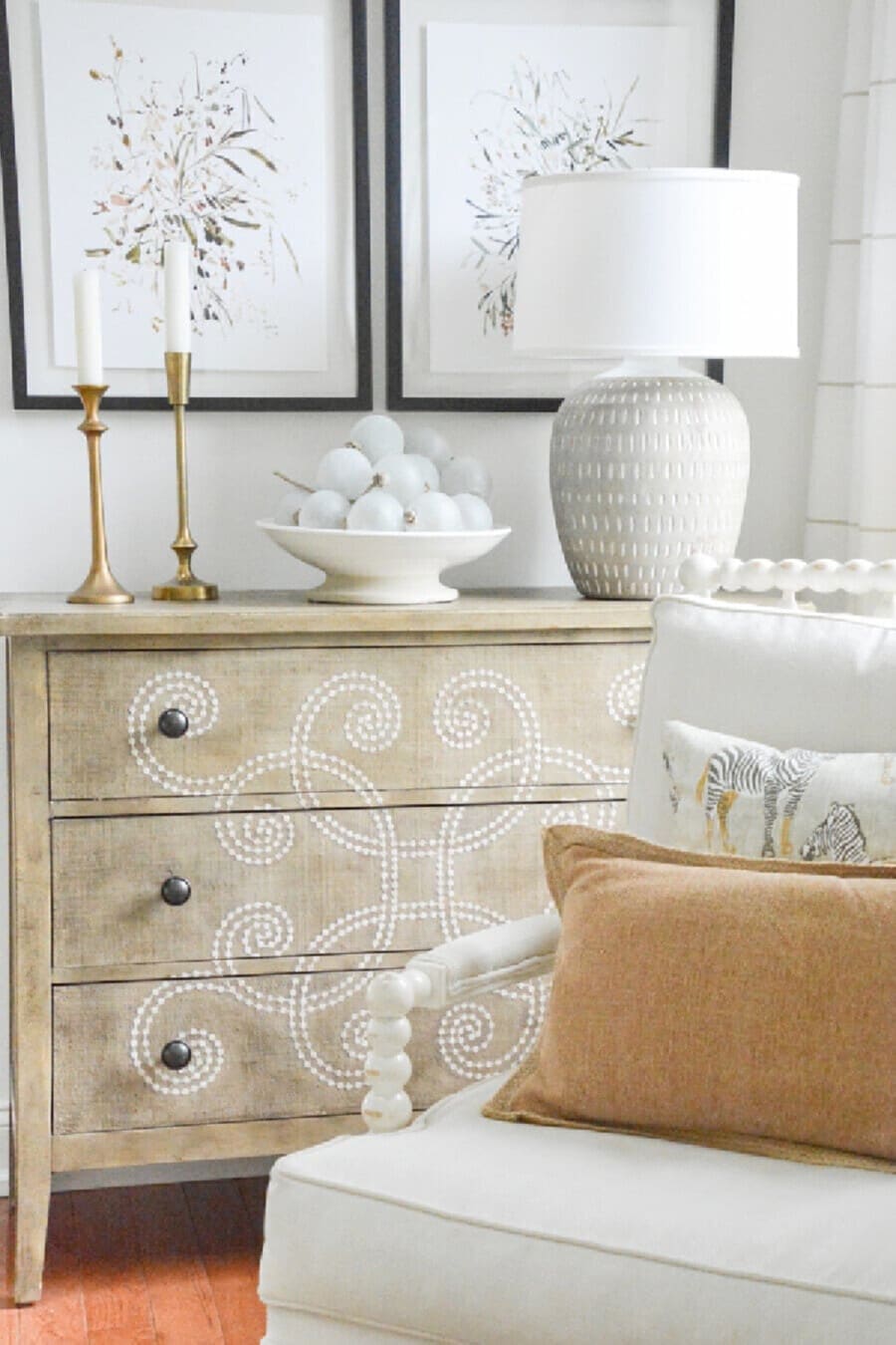 chest with pictures in back of it. Chair in the foregtround.