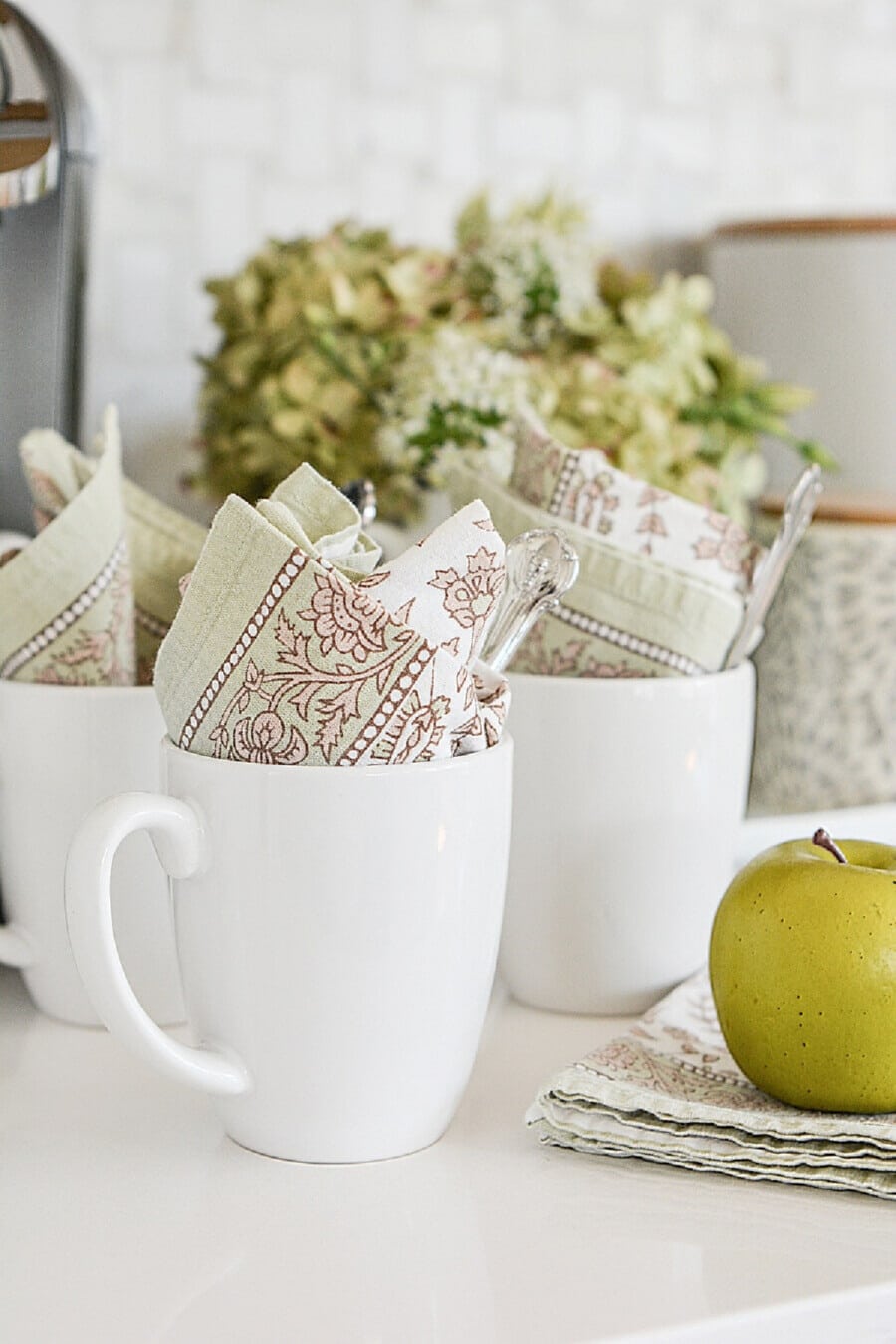 white mugs with light green and beige napkins in them