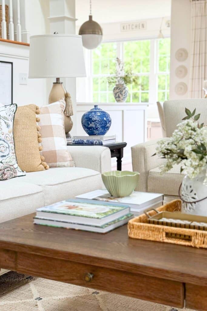 Open concept living room with green and cream mixed pattern pillows on a sofa facing an armchair with a monogrammed pillow
