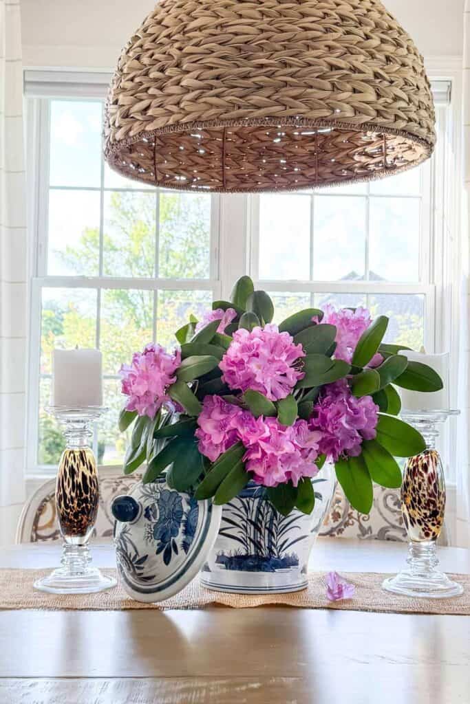 Blue and white ginger jar filled with two fresh rhododendron branches as an easy dining table centerpiece