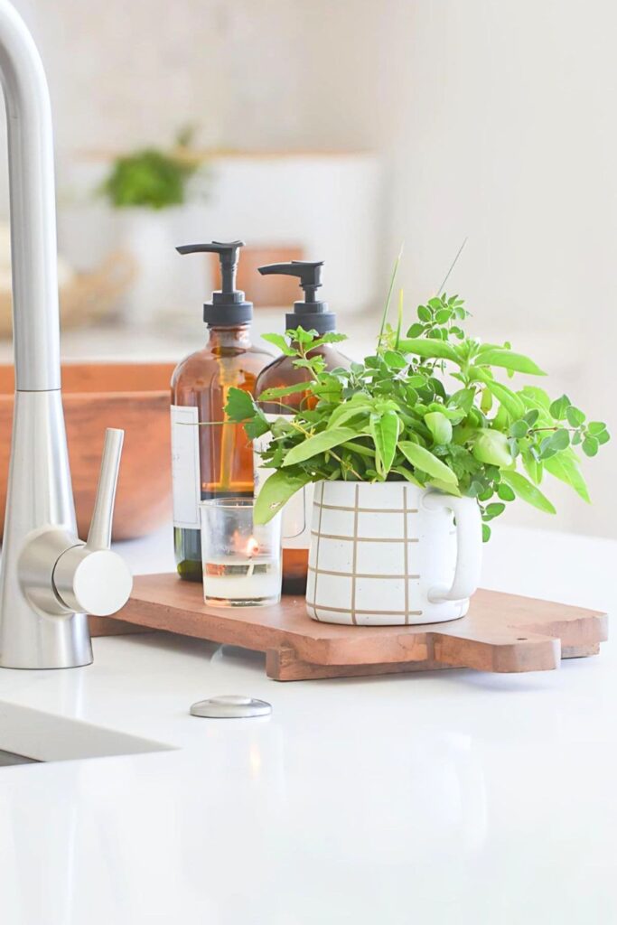 Fresh herbs in a mug on a wood tray at the kitchen sink for late summer decorating