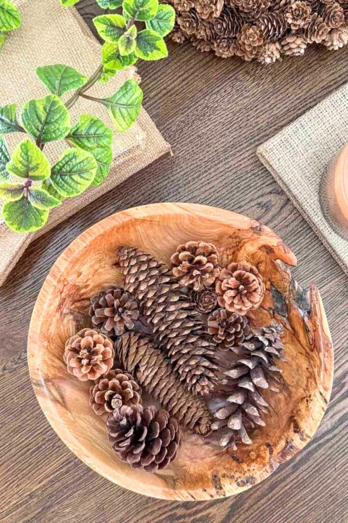 Foraged pinecones in a wood bowl on a table for late summer decorating
