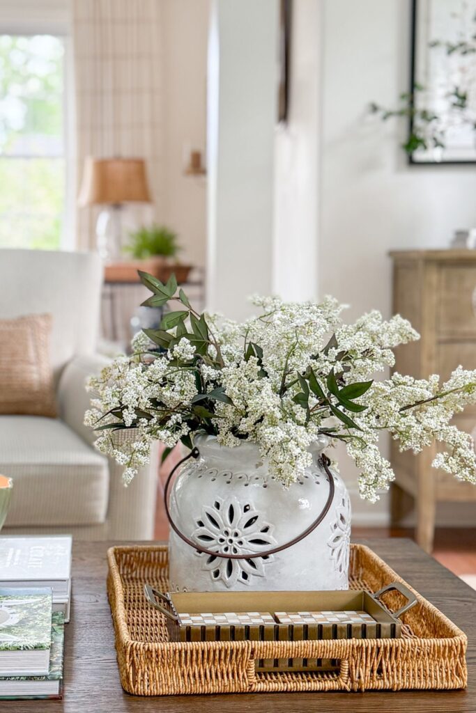 Coffee table styled with a tray, vase of flowers, and stacked books in a small home