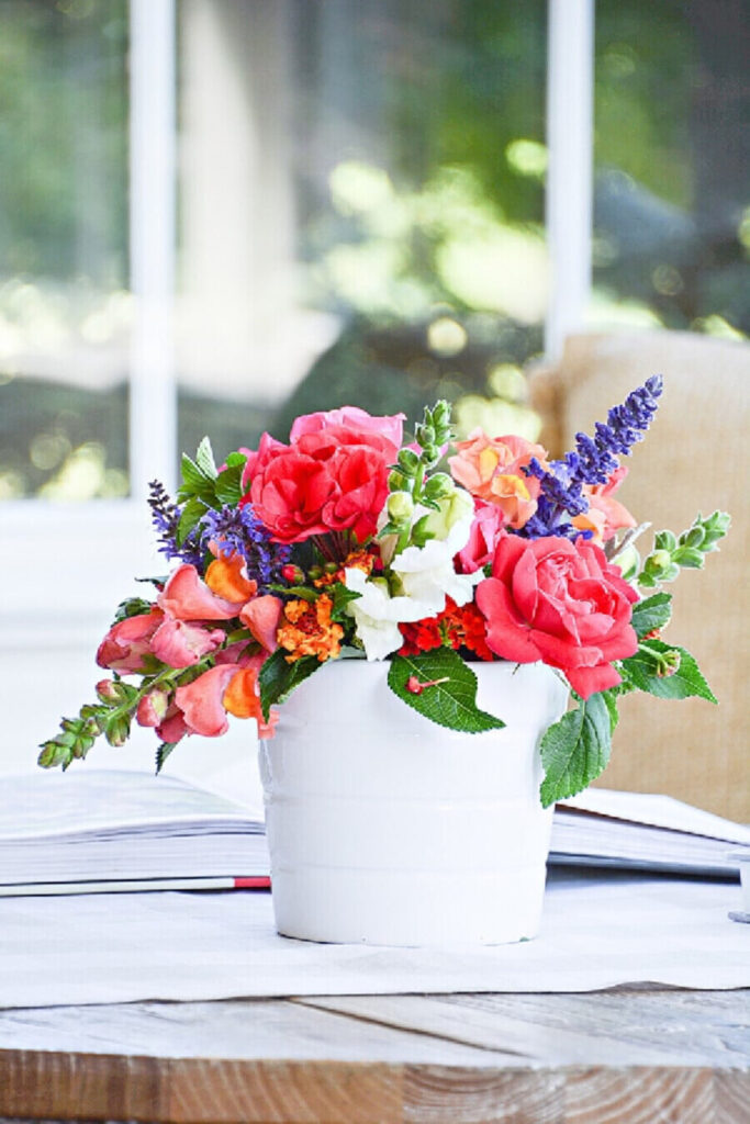 Fresh cut garden flowers in a white pot on a coffee table for late summer decorating