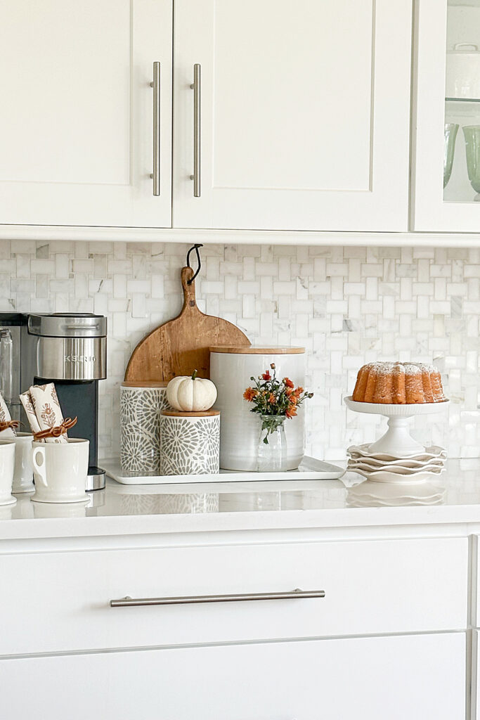 SIMPLE FALL COFFEE BAR WITH COFFEE MAKER, CUPS WITH NAPKINS INSIDE THEM, CANISTERS AND A BUNDT CAKE
