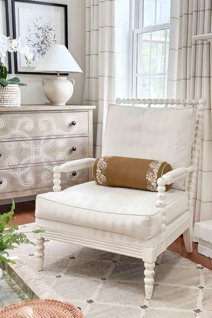 GOLD FALL BOLSTER PILLOW ON A WHITE SPINDLE CHAIR