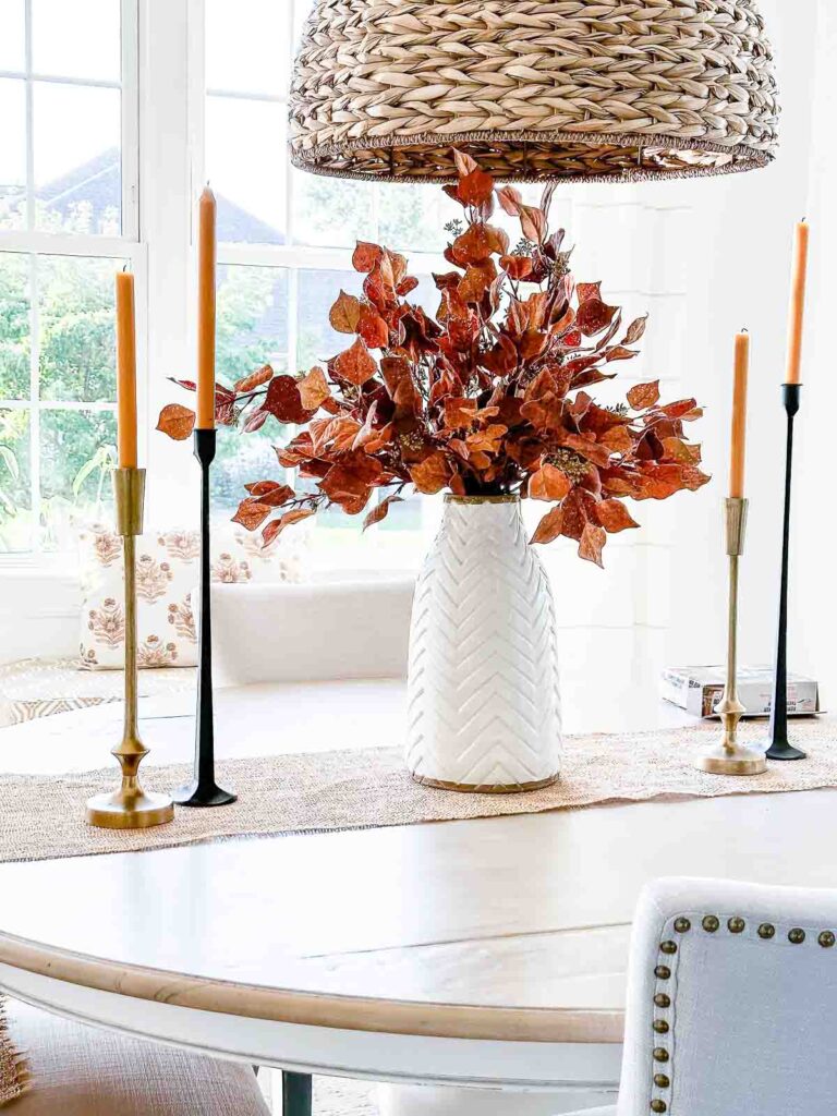 LARGE WHITE VASE WITH BURNT ORANGE FALL LEAVES IN IT