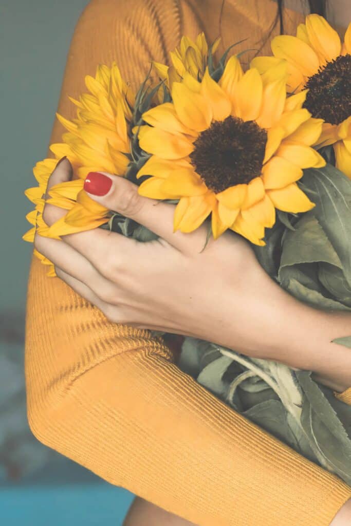 WOMAN HOLDING SUNFLOWERS IN HER ARMS