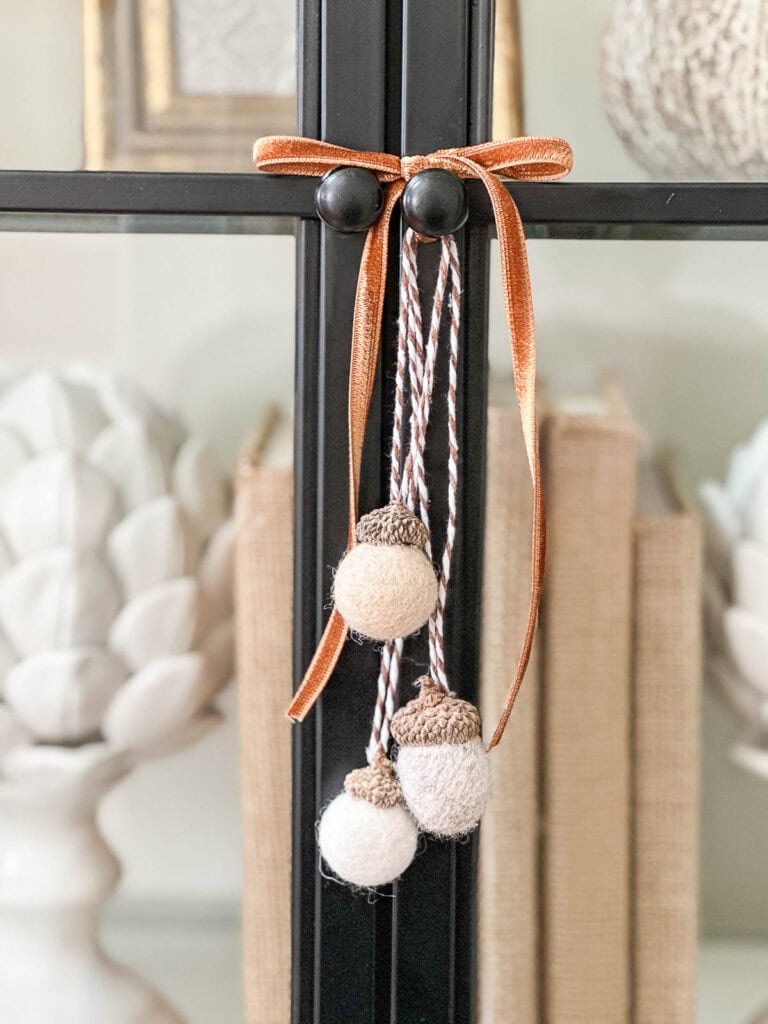 wool ball acorns tied with a velvet ribbon on the doors of a bookcase