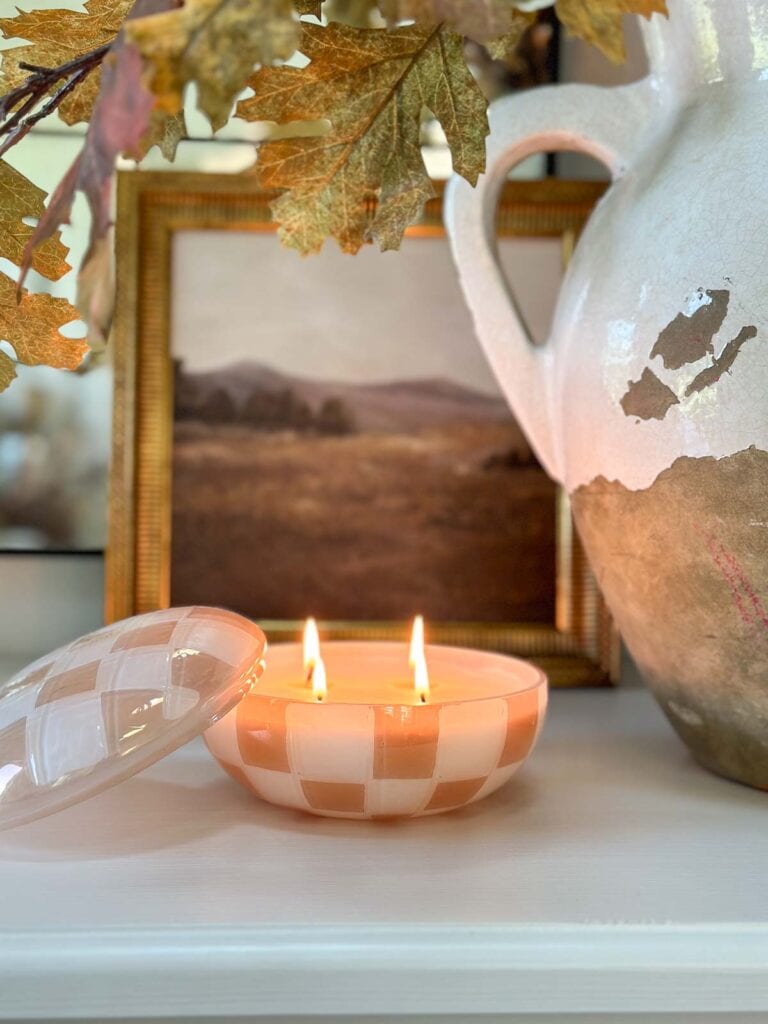 a lit candle and an urn of fall leaves