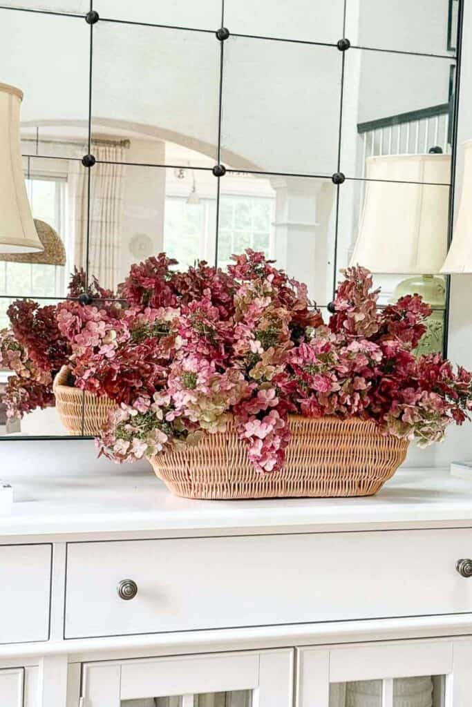 Basket of dried pink and green hydrangeas styled on a console table for fall
