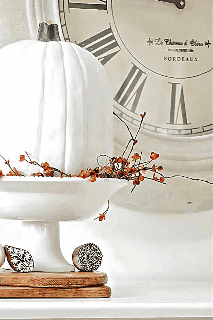 White pumpkin in a footed bowl surrounded by bittersweet vines