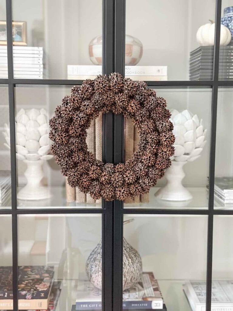 SWEET GUM BALL WREATH ON ON THE FRONT OF A GLASS BOOKCASE
