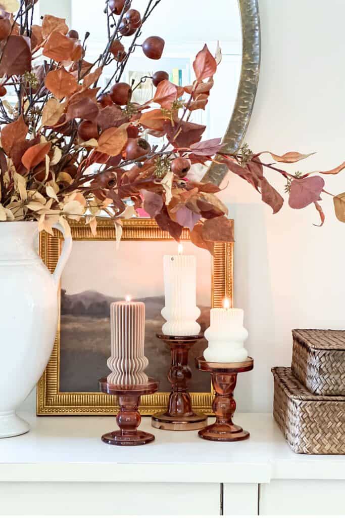 Fall foyer decorating idea with a white urn of autumn branches, candles on stands, and simple seasonal accents.