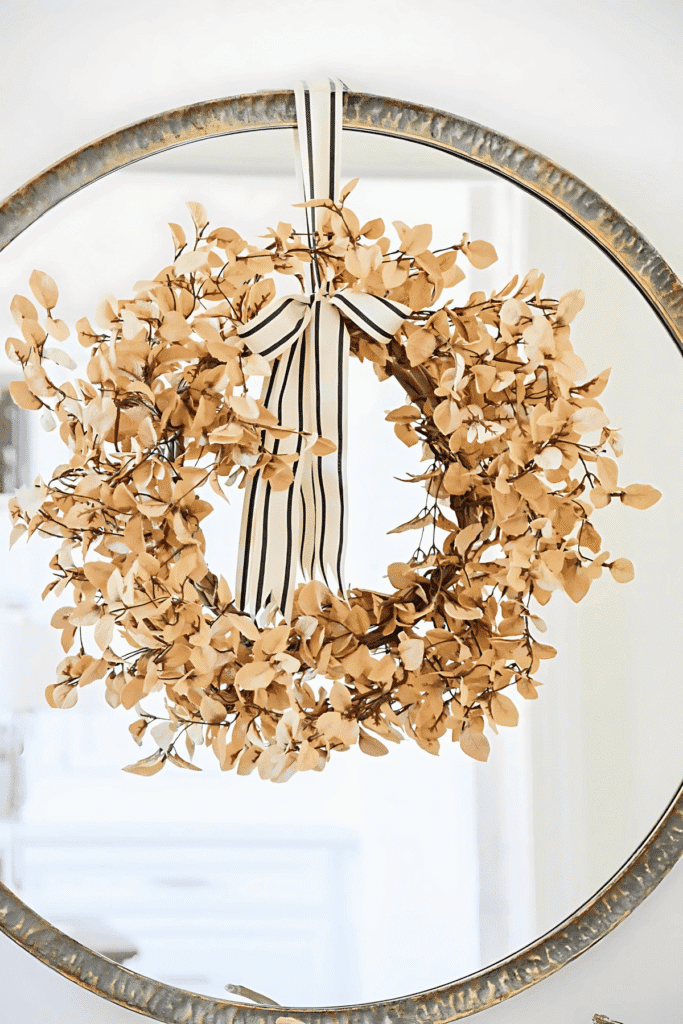 Understated wreath tied with ribbon and styled on a mirror for fall decorating