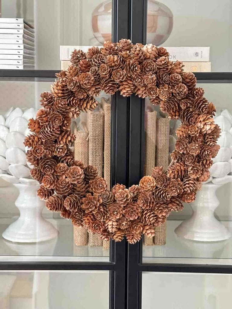 pinecone wreath hanging on a glass front  bookcase