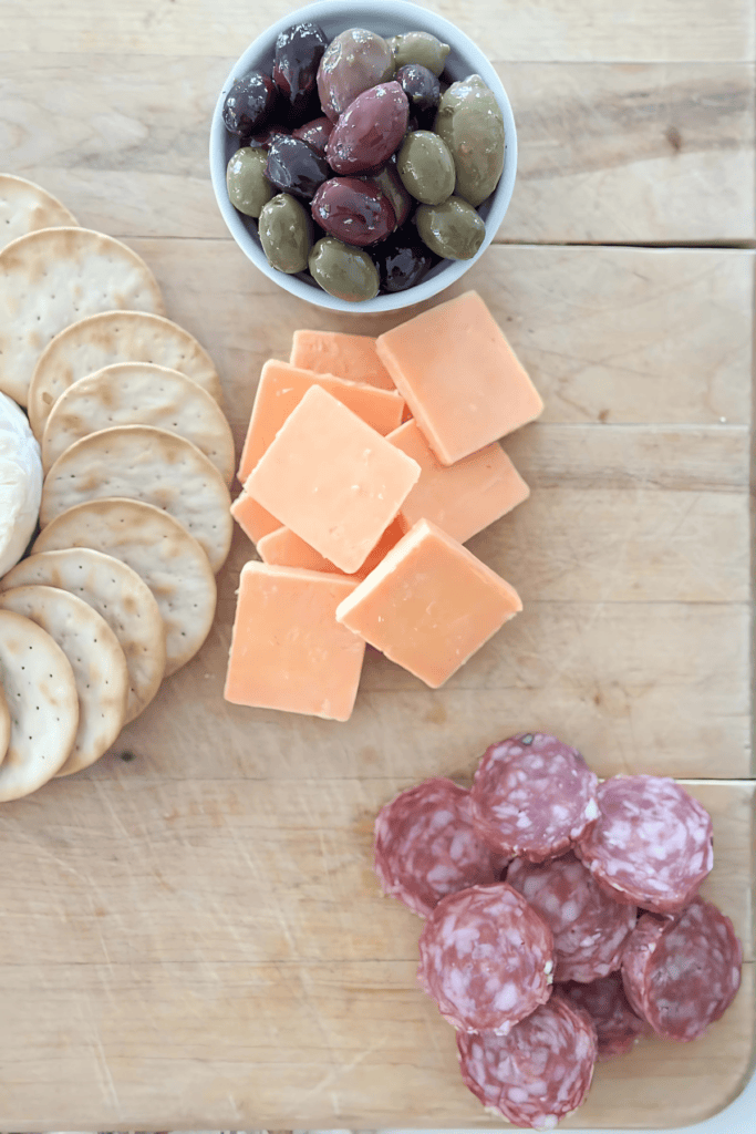 soft cheese surrounded by crackers and olives