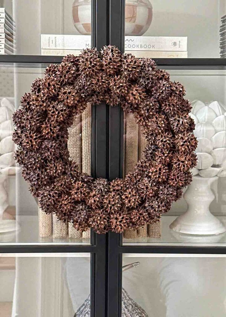 sweet gum ball wreath hanging on a glass bookcase door.