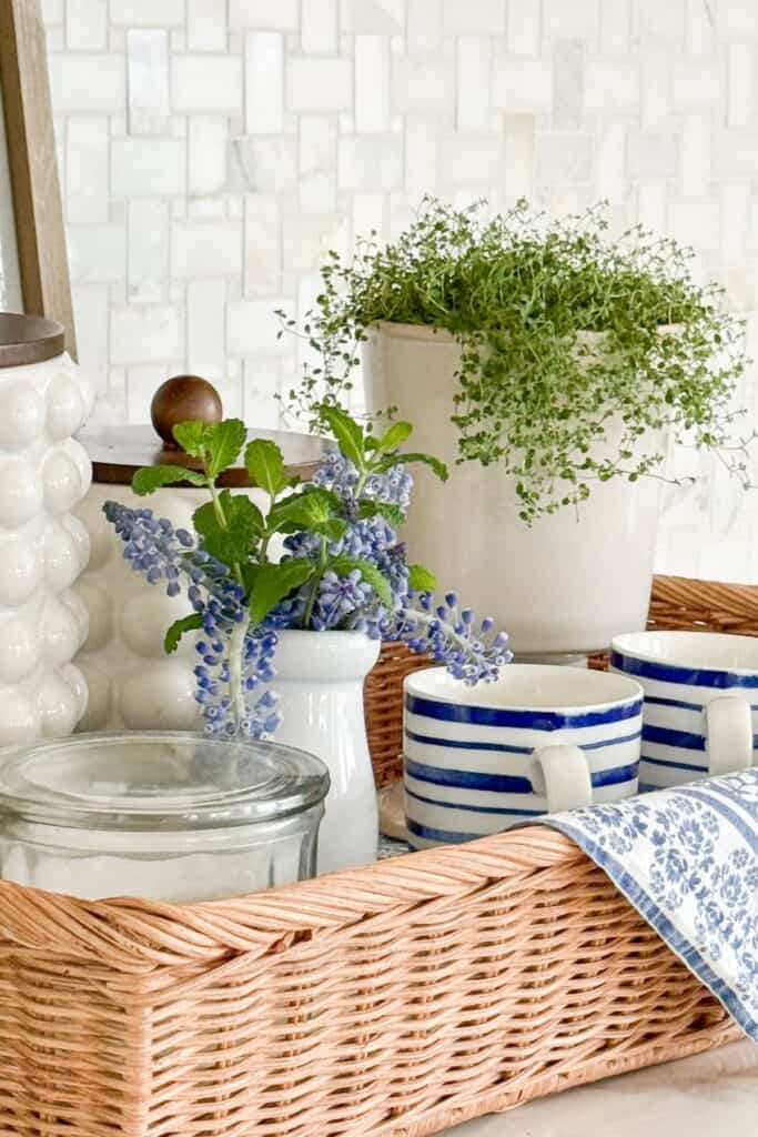 woven basket organizing kitchen items with mugs, jar, and plant on a clean counter