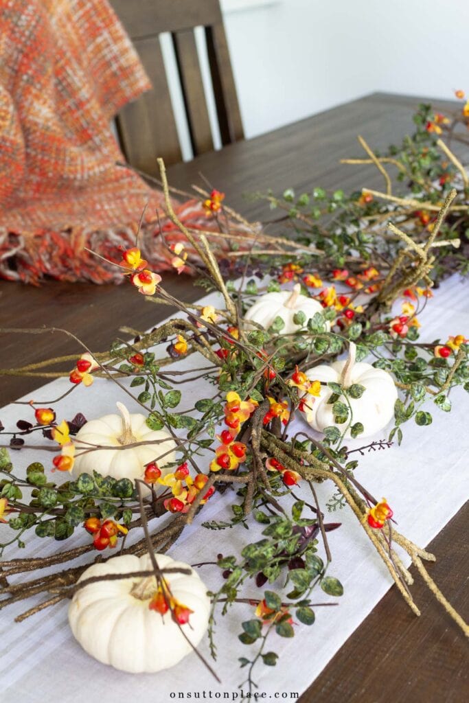 a table with a pumpkin and bittersweet centerpiece