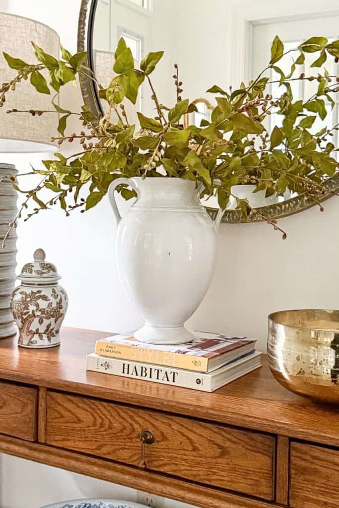 organized console table with white vase, greenery, stacked books, and simple decor for a clutter free home