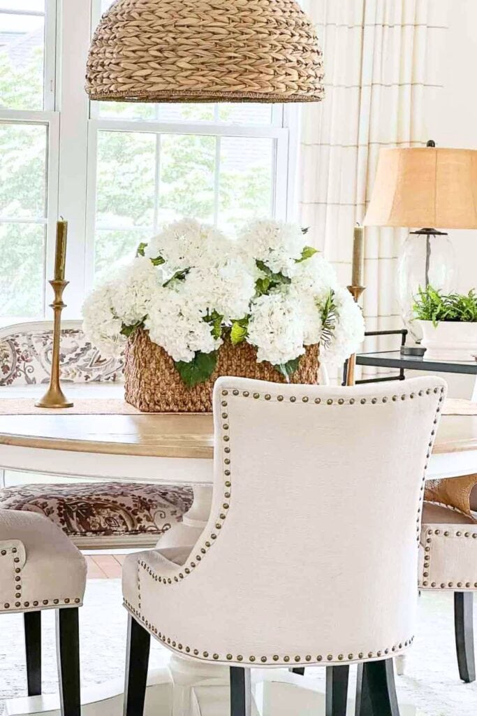 organized dining table with simple centerpiece of white hydrangeas in a basket and minimal decor