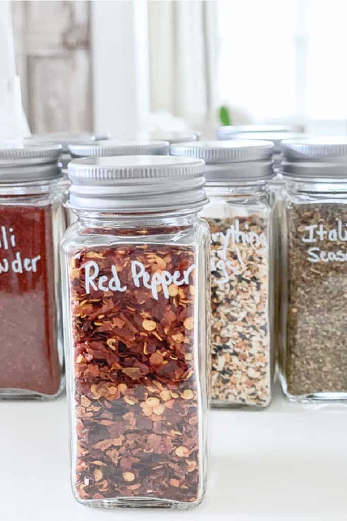 organized spice jars labeled in clear containers for easy kitchen organizing and storage