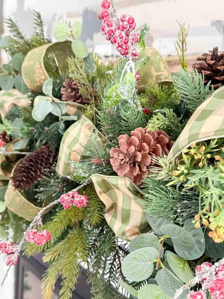 A close look at this lush Christmas garland shows how pretty faux Christmas greens, berries, pinecones, and ribbon can look when layered together.