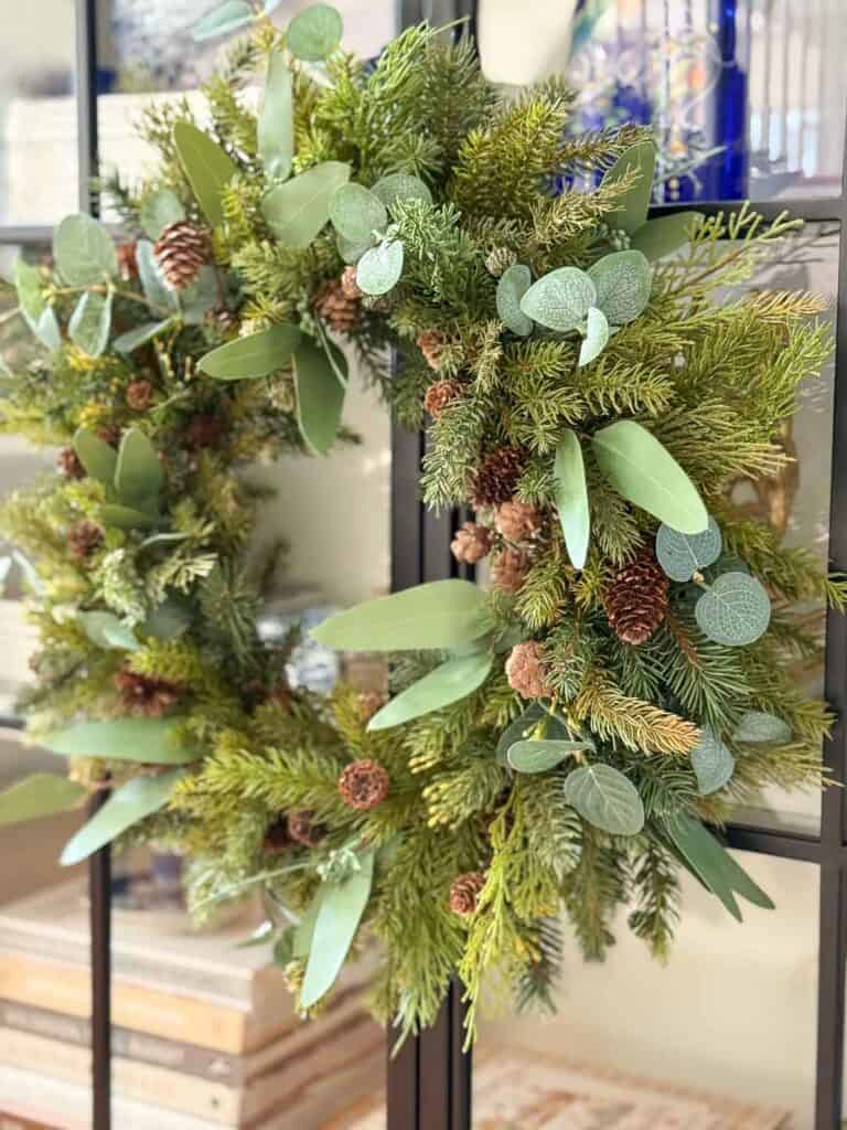 Faux evergreen and eucalyptus Christmas wreath with pinecones hanging on a glass bookcase door