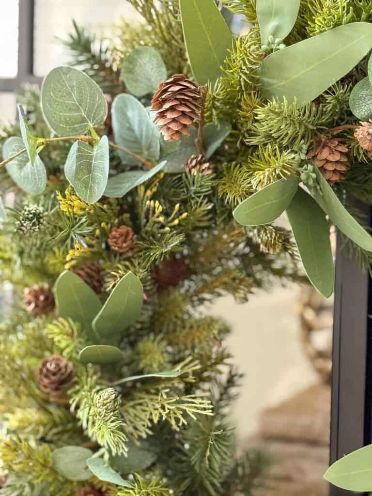 Close up of a faux Christmas wreath with evergreens, eucalyptus, and pinecones