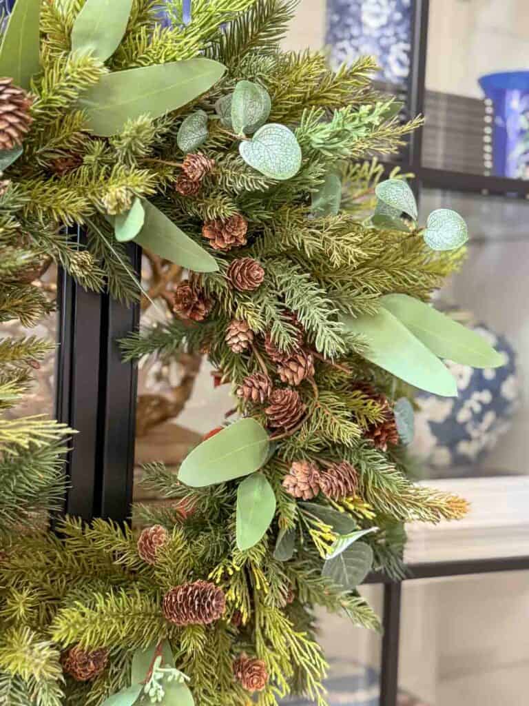 Close up of a Christmas wreath made with faux evergreens, pinecones, and eucalyptus leaves