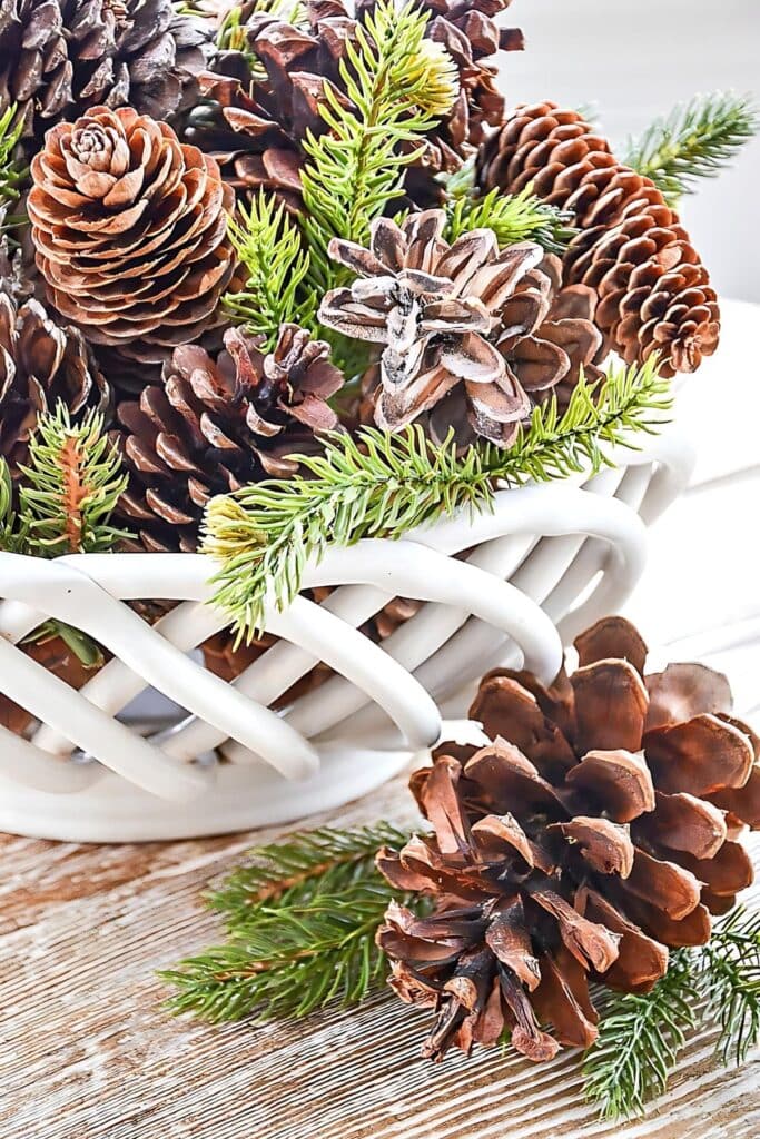 Christmas DIY-scented pinecones with greens in a white ceramic basket