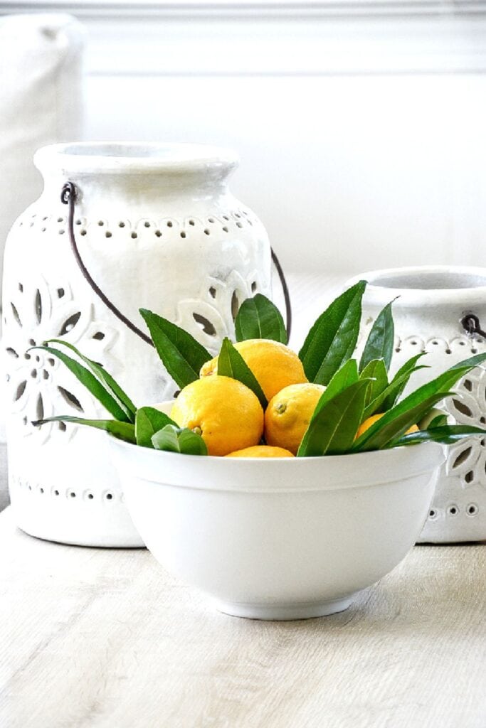 lemon in a white bowl with lemon leaves