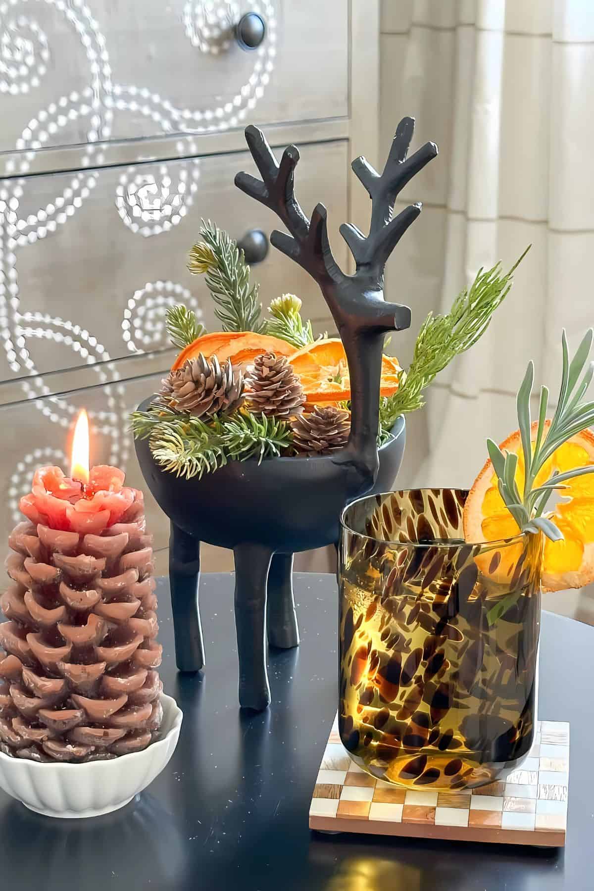 reindeer bowl with greens and dried oranges and other decor on a drink table