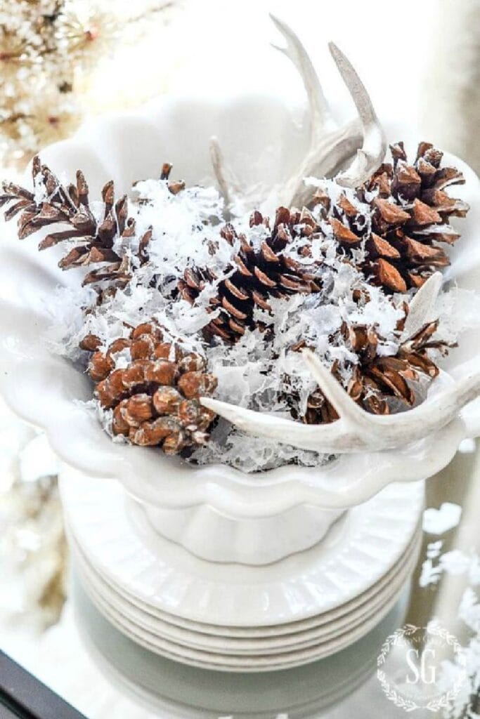 3- step Christmas arrangement: a white footed bowl, pinecones, and deer sheds