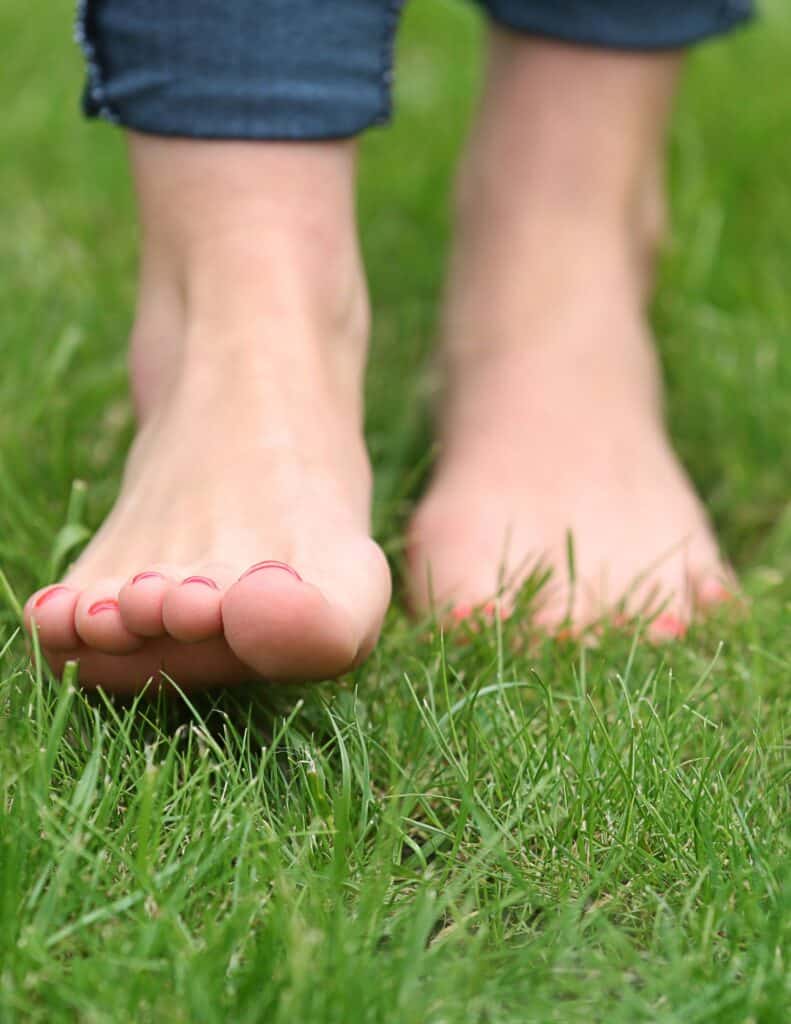 woman walking barefoot in the grass