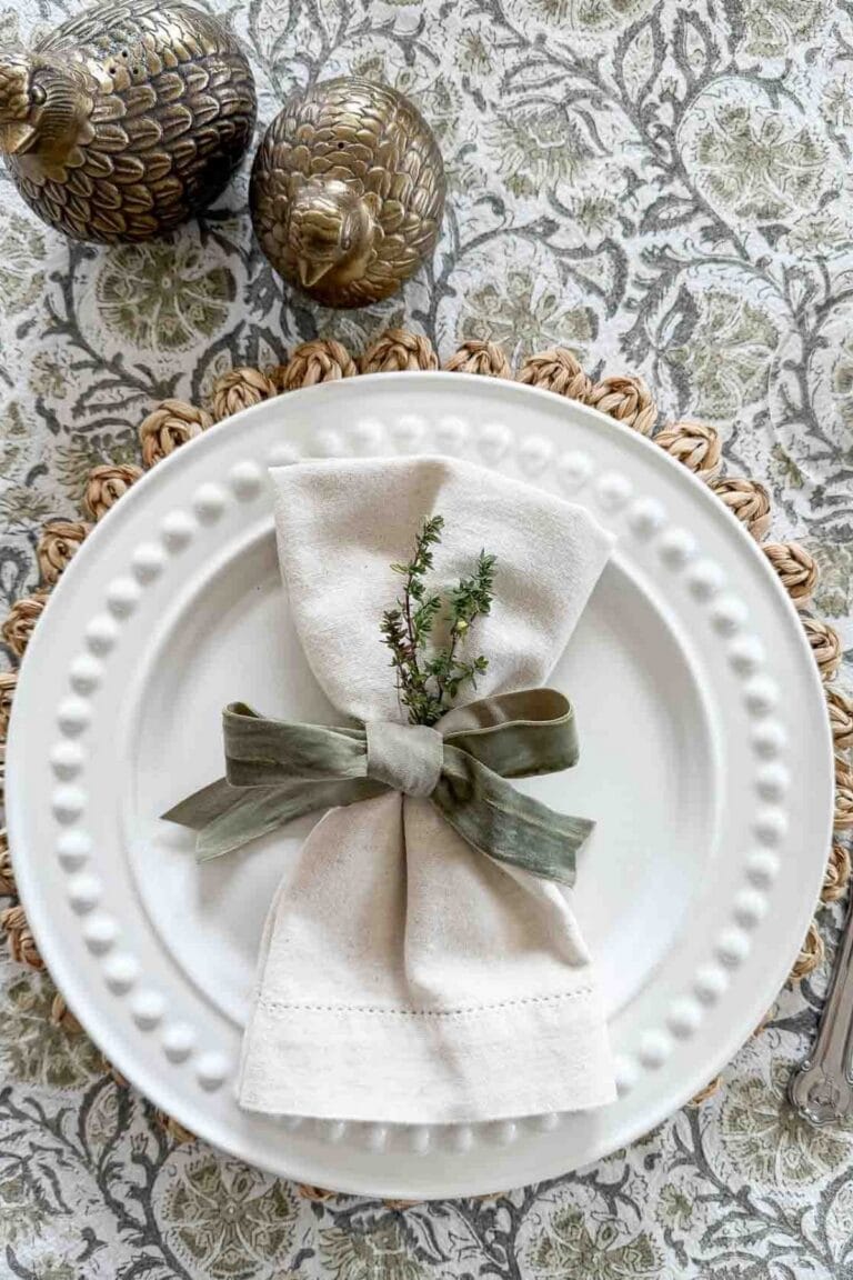 green and white place setting with a bow tied napkin and a sprg of thyme