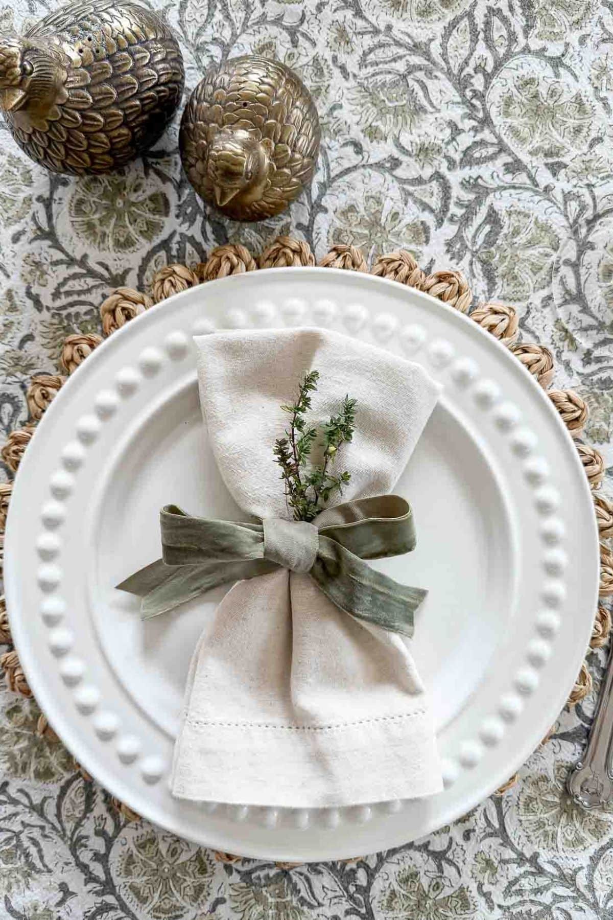 green and white place setting with a bow tied napkin and a sprg of thyme