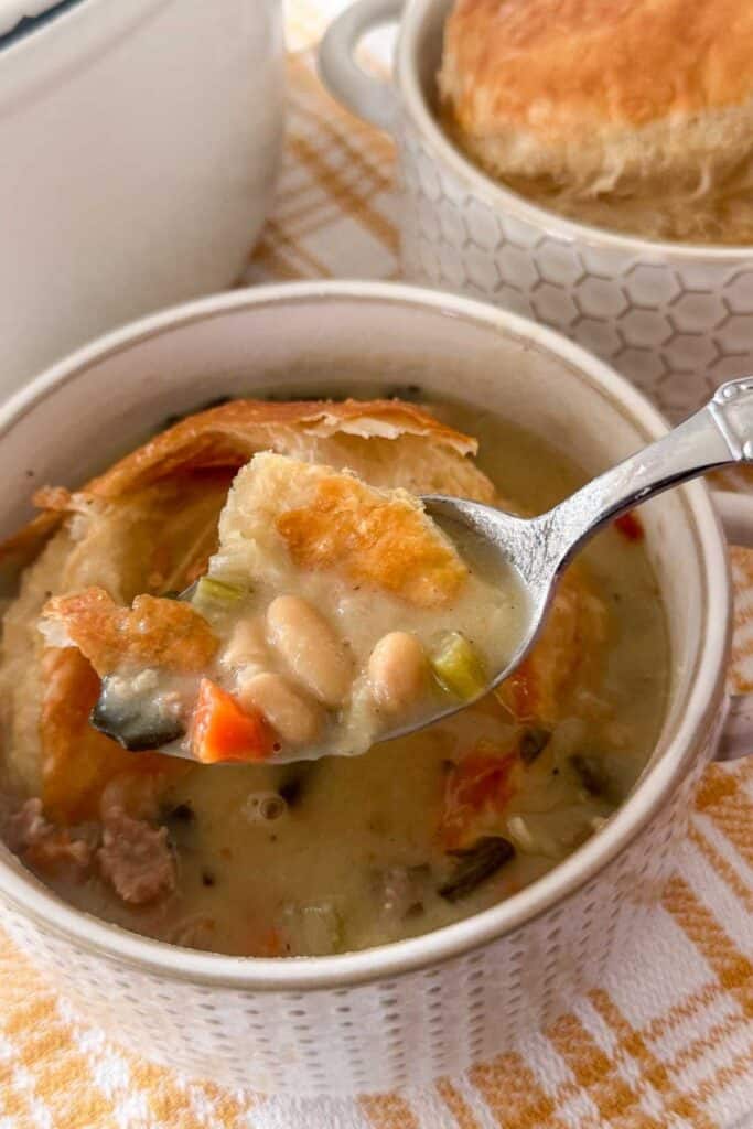 a spoonful of soup with beans, swiss kale and sausage.