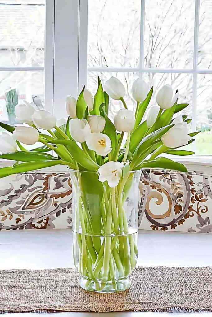 white tulips in a glass vase on the dining room table